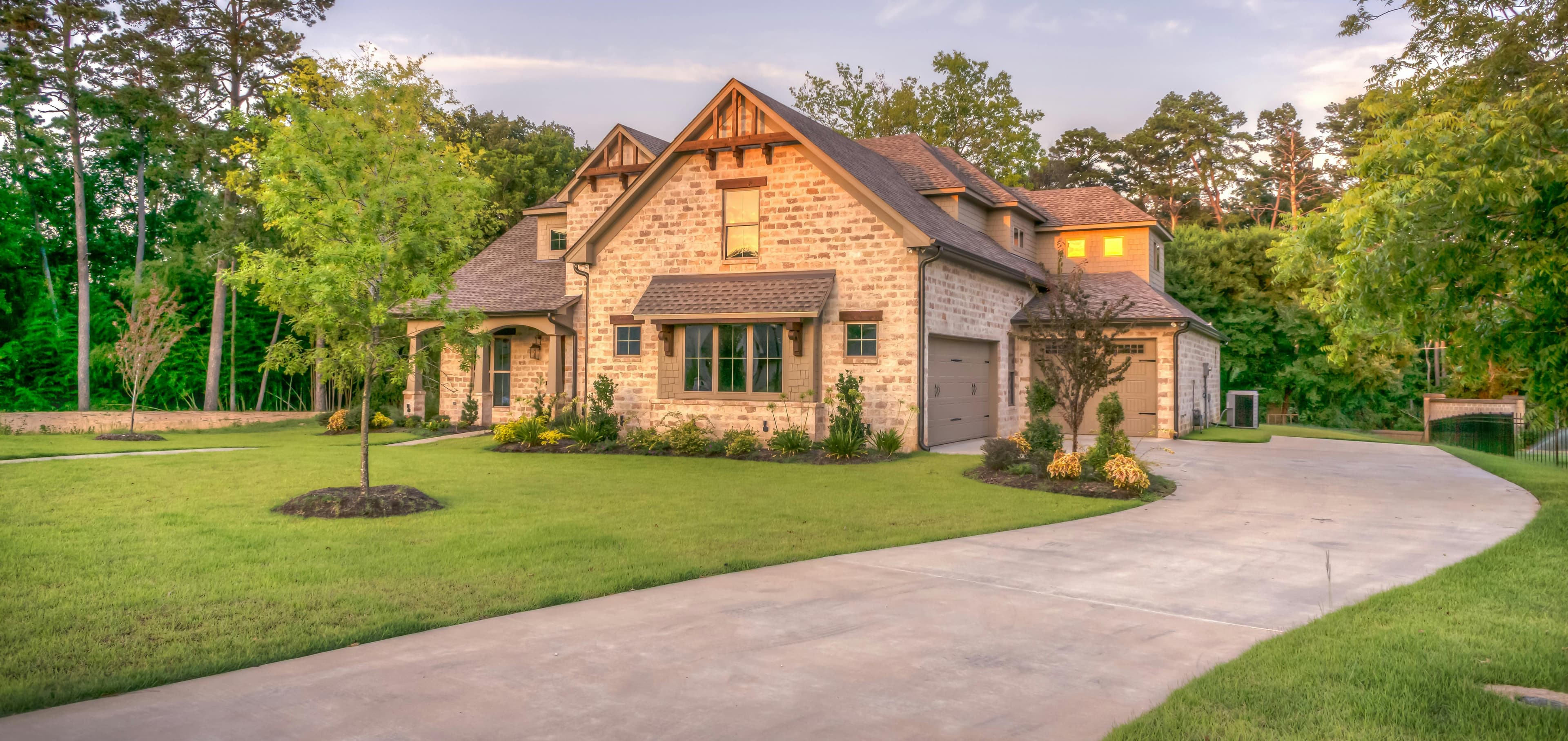 Beautiful residential property with a curved concrete driveway surrounded by manicured lawn and landscaping